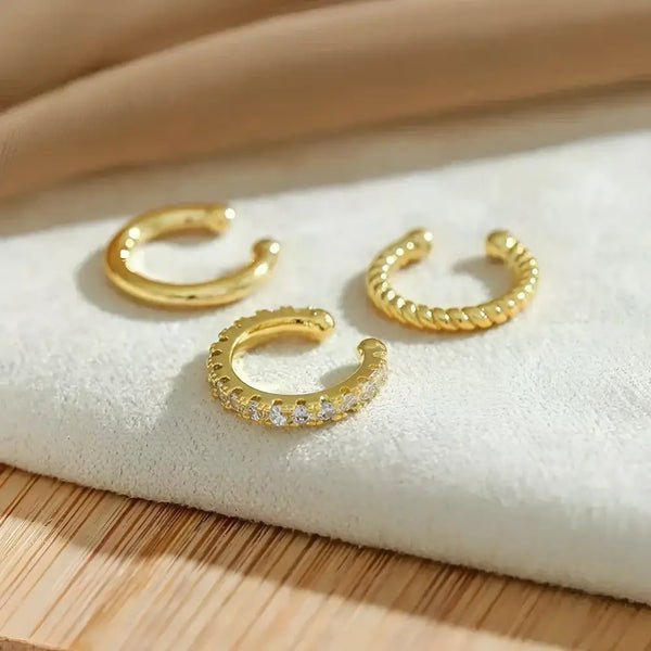 Three gold-colored ear cuffs.