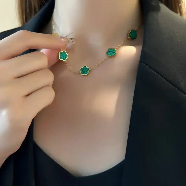 Gold necklace with green clover pendants.