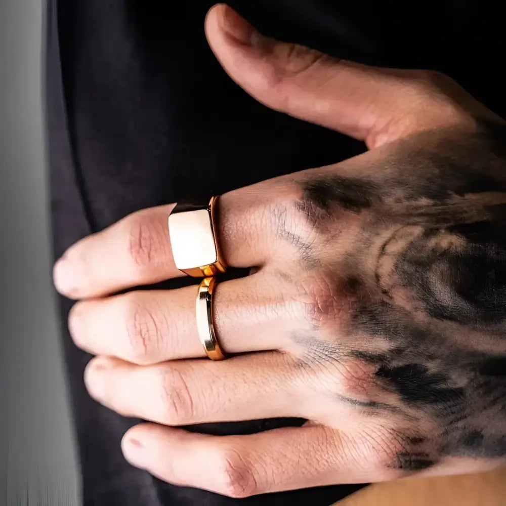 Gold rings on tattooed hand.