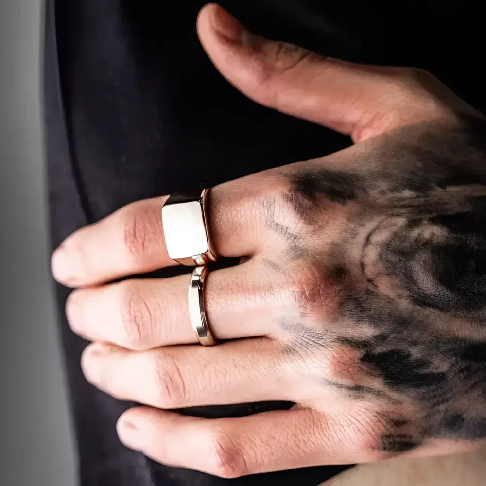Tattooed hand with gold rings.