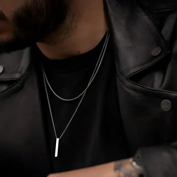 Man wearing two silver necklaces.