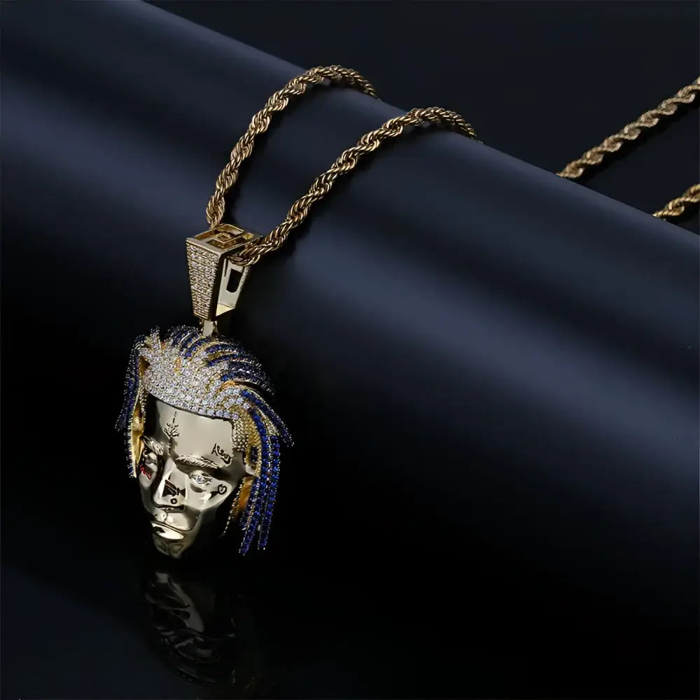 Gold chain with a jeweled pendant of a person’s face.