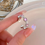 Silver ring with pink heart accents.