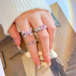 Hand adorned with silver rings featuring pink gemstones.