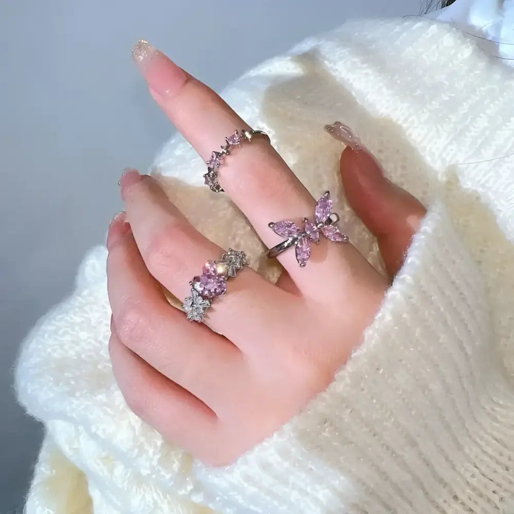 Hand adorned with pink gemstone rings.