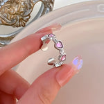 Silver ring with pink heart accents.