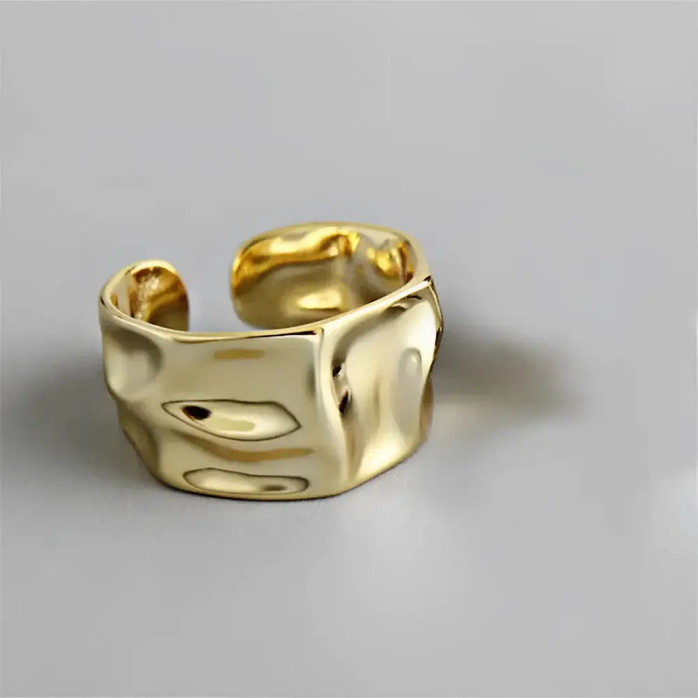 Gold-colored, textured, open-ended ring.