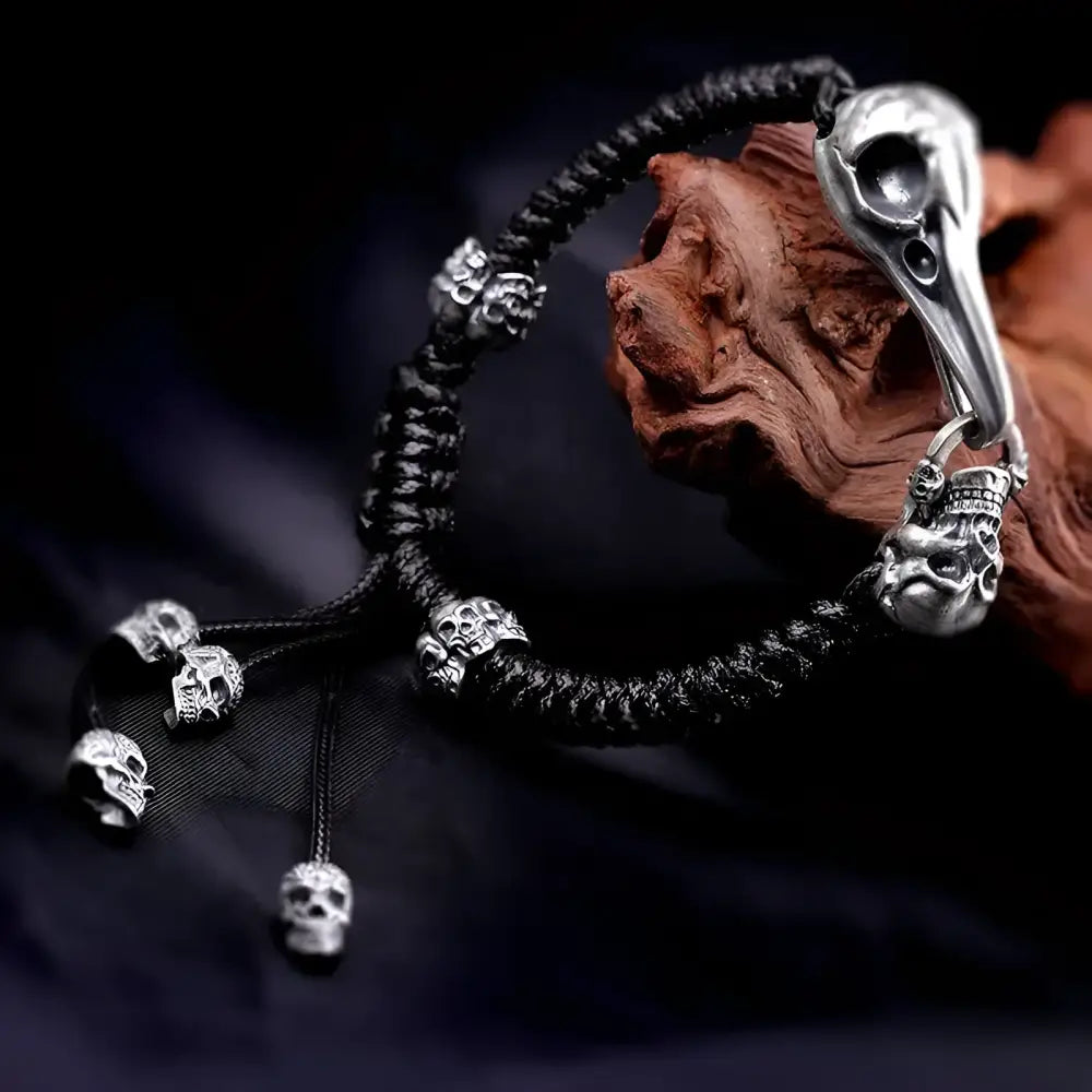 Black braided bracelet with silver skull accents and bird skull pendant.