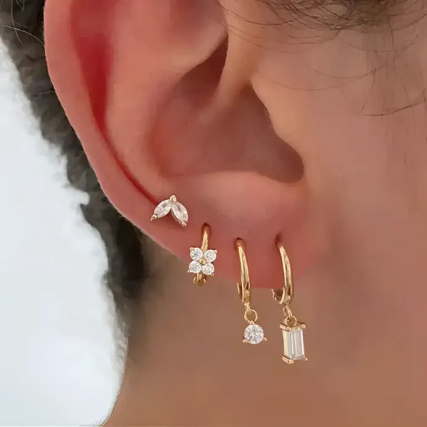Ear with multiple gold and gemstone earrings.