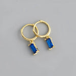 Gold hoop earrings with blue rectangular gems.