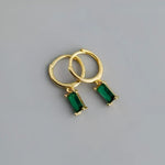 Gold hoop earrings with emerald pendants.