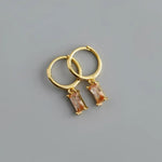 Gold hoop earrings with rectangular peach-colored gems.