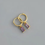 Gold hoop earrings with purple rectangular gems.