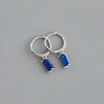 Silver hoop earrings with blue rectangular gems.