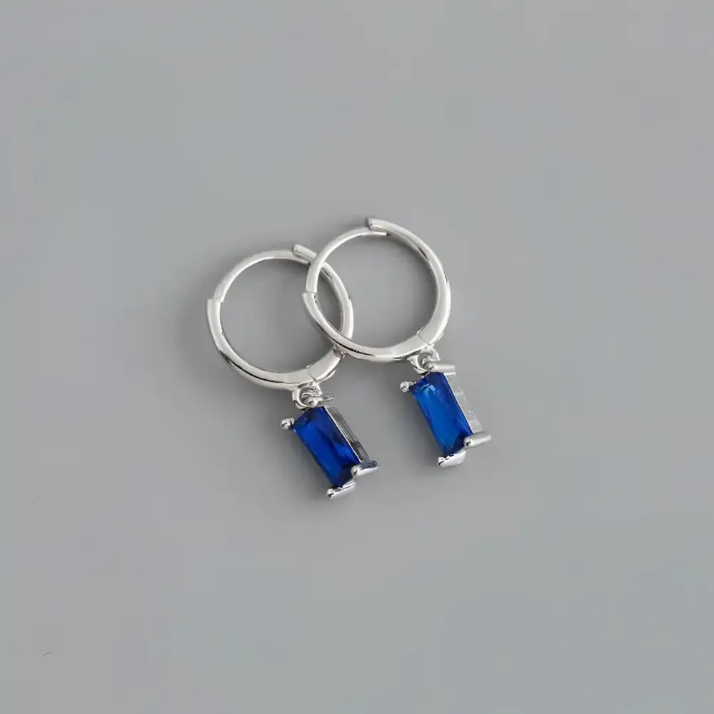 Silver hoop earrings with blue rectangular gems.
