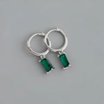 Silver hoop earrings with emerald pendants.