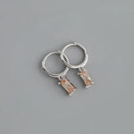 Silver hoop earrings with peach-colored rectangular gems.