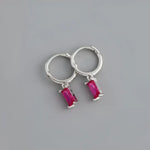 Silver hoop earrings with pink rectangular gems.