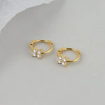 Pair of gold hoop earrings with clover-shaped diamond accents.