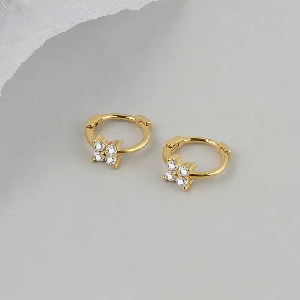 Pair of gold hoop earrings with clover-shaped diamond accents.