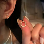 Circular gold stud earrings.