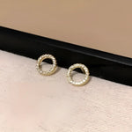Circular gold earrings with embedded crystals.