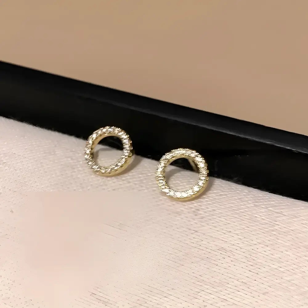 Circular gold earrings with embedded crystals.