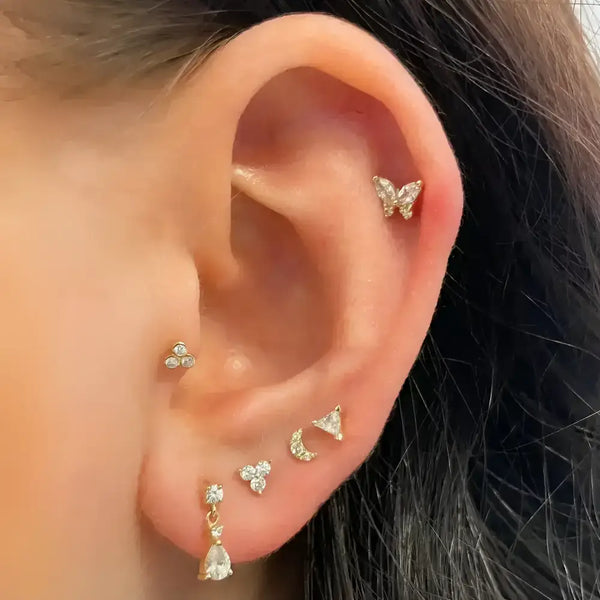 Ear with multiple gold and diamond earrings.