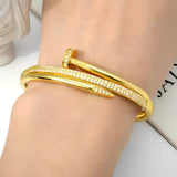 Gold nail-shaped bracelet with embedded crystals.