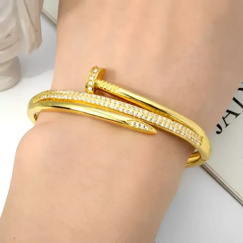 Gold nail-shaped bracelet with embedded crystals.